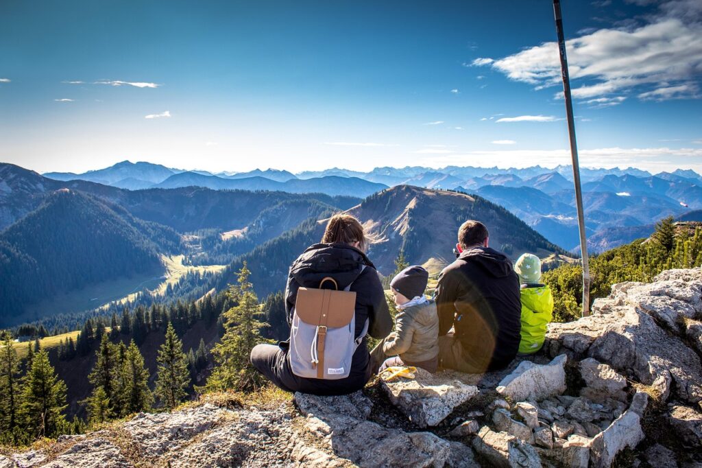 une famille avec deux enfants assise au bord des rochers dans les montagnes